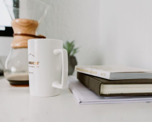 A neat stack of notebooks and a coffee cup on a brightly lit desk in a creative office space in Mexico City