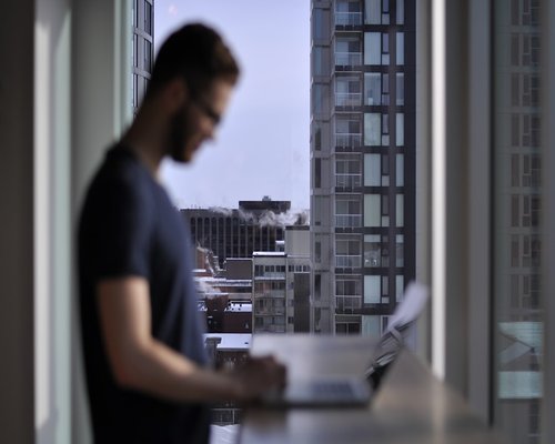 A person taking a break from their laptop, looking thoughtfully out the window of their apartment